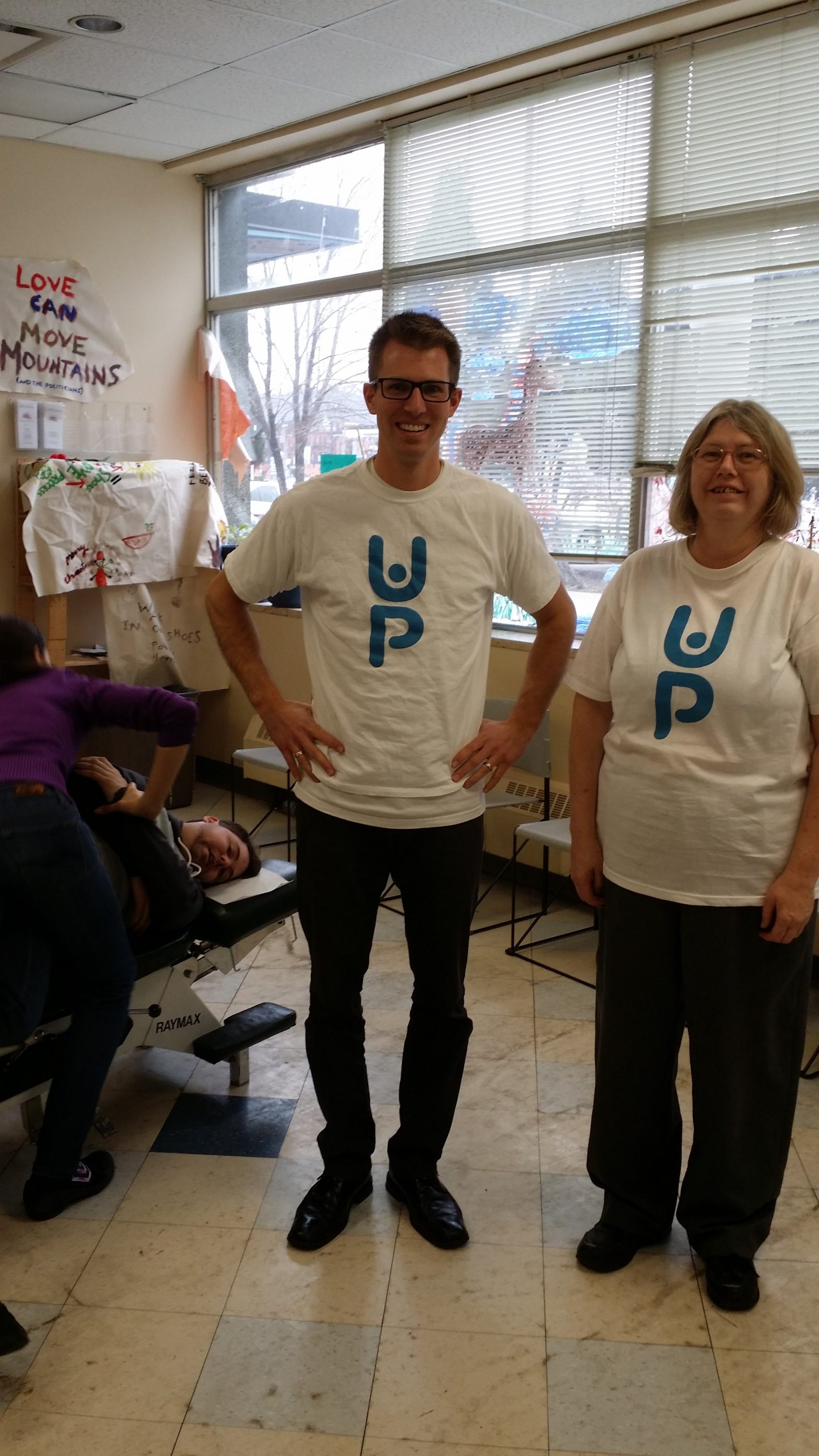 Dr. Callum Peever laughing at the Hamilton Urban Core Community Health Centre Volunteer Chiropractic Clinic with Karen