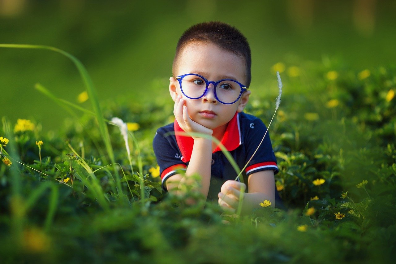 kid with glasses in naturally green field